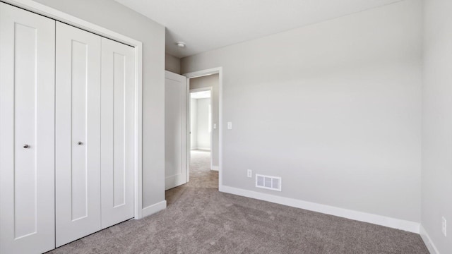 unfurnished bedroom featuring light colored carpet and a closet