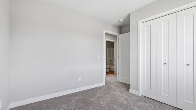 unfurnished bedroom featuring a closet and light colored carpet