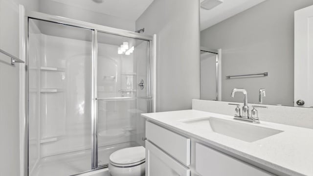 bathroom featuring vanity, an enclosed shower, and toilet