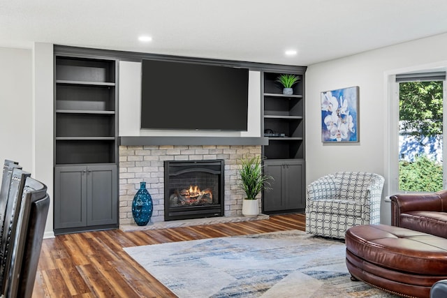 living room with dark wood-type flooring, a fireplace, and built in features