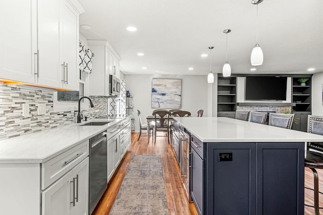 kitchen featuring sink, white cabinets, a kitchen breakfast bar, hanging light fixtures, and a spacious island