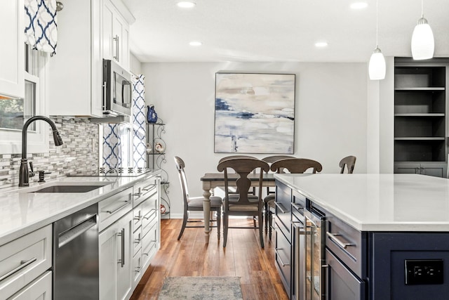 kitchen featuring appliances with stainless steel finishes, decorative light fixtures, sink, wine cooler, and white cabinets