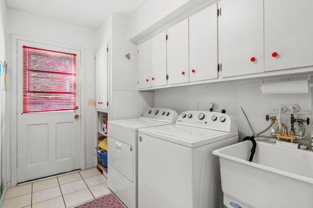 laundry area with light tile patterned floors, sink, washing machine and dryer, and cabinets