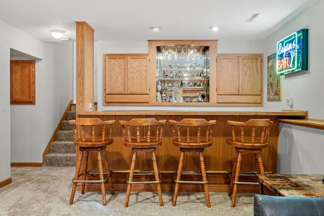 bar with light carpet and light brown cabinets