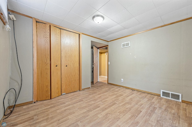 unfurnished bedroom with light hardwood / wood-style flooring, a closet, and crown molding