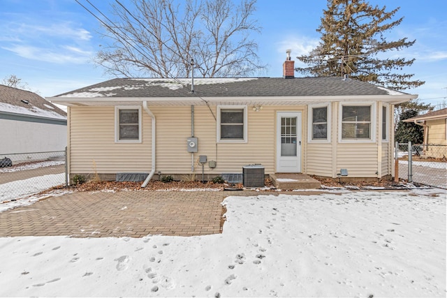 snow covered house featuring central AC unit