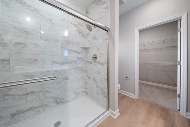 bathroom featuring a shower with door, wood-type flooring, and toilet