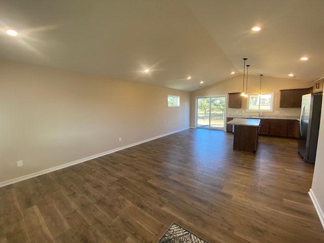 kitchen with dark hardwood / wood-style flooring, a center island, stainless steel refrigerator, hanging light fixtures, and lofted ceiling