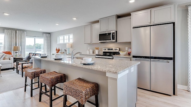 kitchen with a kitchen breakfast bar, stainless steel appliances, and a kitchen island with sink