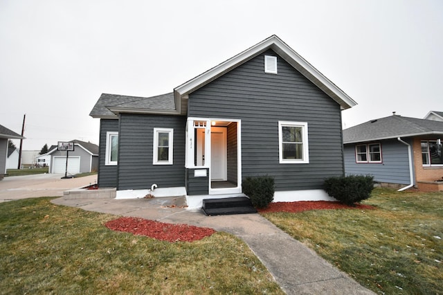 view of front of house featuring a garage, an outdoor structure, and a front lawn