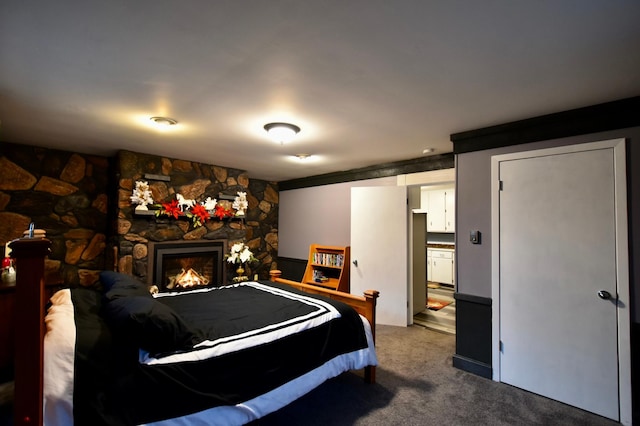 bedroom with a stone fireplace and carpet