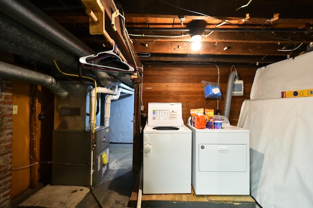 clothes washing area with wooden walls, washing machine and dryer, and heating unit