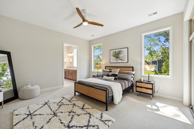 carpeted bedroom featuring connected bathroom, ceiling fan, and multiple windows