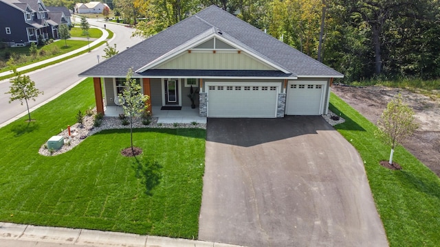 view of front of house featuring a garage, covered porch, and a front lawn