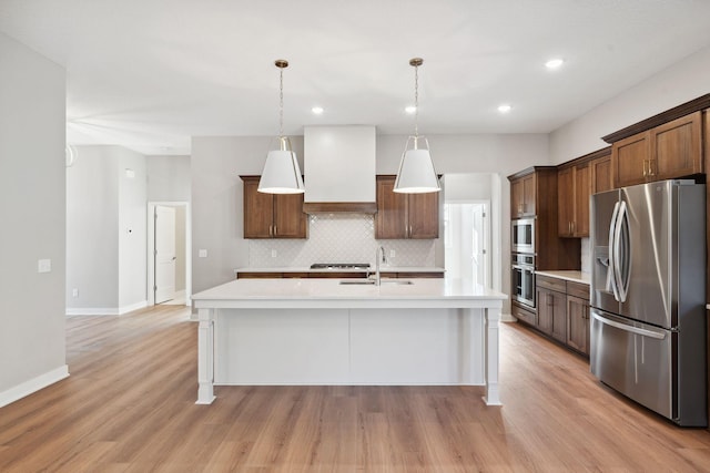 kitchen featuring pendant lighting, sink, stainless steel appliances, an island with sink, and custom exhaust hood