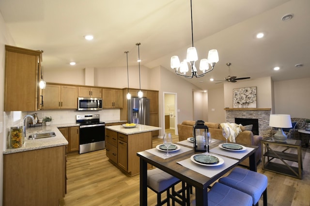 kitchen with a stone fireplace, stainless steel appliances, decorative backsplash, sink, and a center island