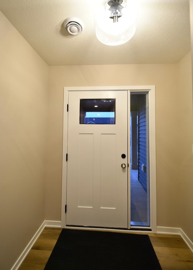 doorway with dark wood-type flooring and a textured ceiling