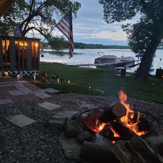 yard at dusk featuring a fire pit and a water view