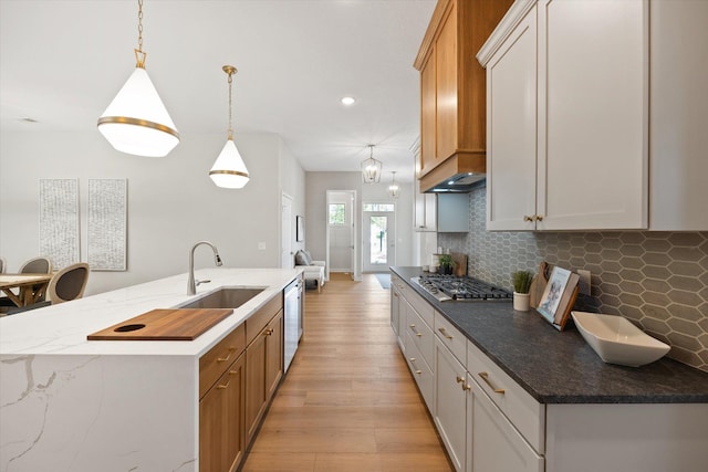 kitchen featuring sink, stainless steel appliances, decorative light fixtures, a center island with sink, and white cabinets