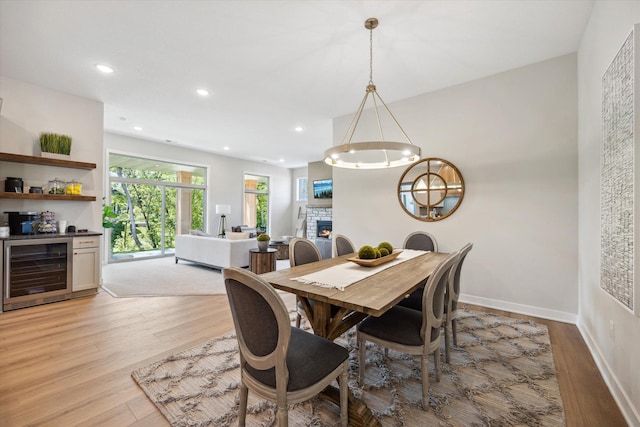 dining area featuring a fireplace, light hardwood / wood-style floors, and wine cooler