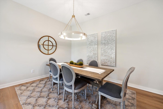 dining space with wood-type flooring and an inviting chandelier