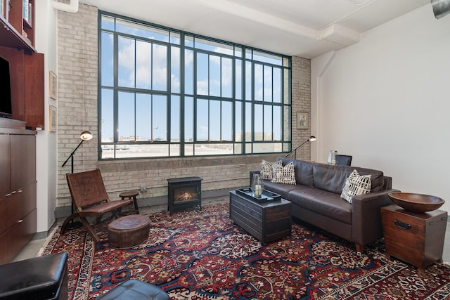 living room featuring brick wall, plenty of natural light, and a wood stove