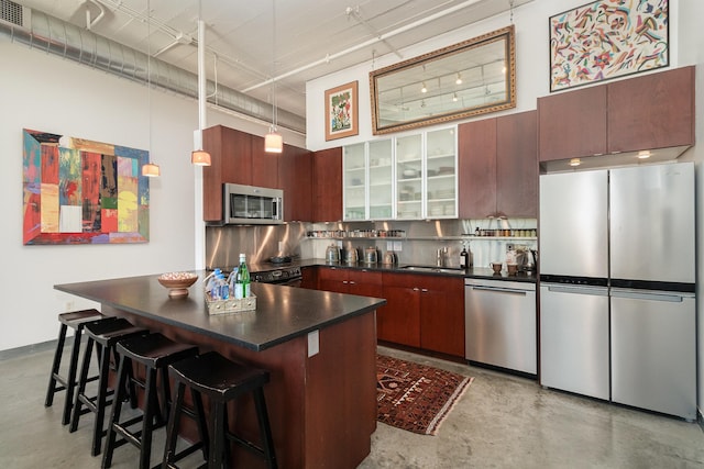 kitchen with a kitchen bar, appliances with stainless steel finishes, pendant lighting, decorative backsplash, and a high ceiling