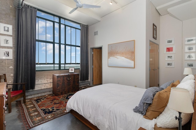 bedroom with ceiling fan, brick wall, concrete flooring, and rail lighting