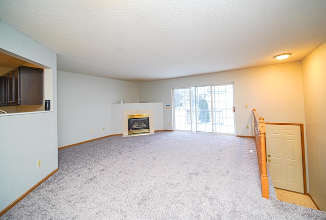 living room featuring a tiled fireplace, light colored carpet, and a textured ceiling