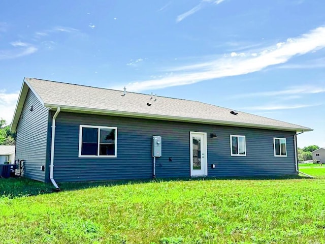 rear view of house featuring cooling unit and a lawn