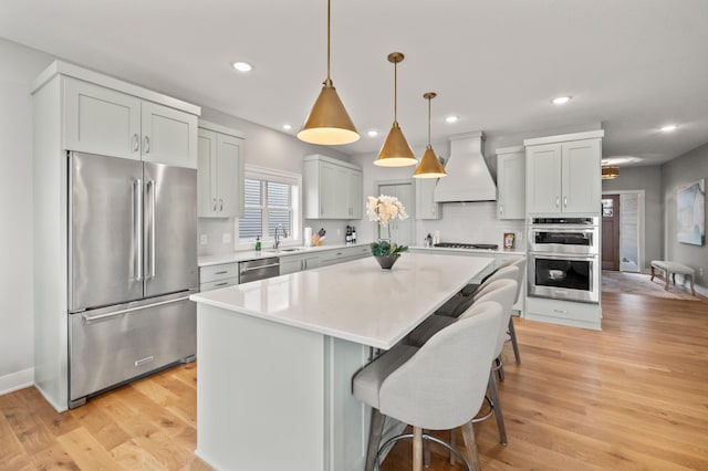 kitchen featuring stainless steel appliances, decorative light fixtures, decorative backsplash, a kitchen island, and custom range hood