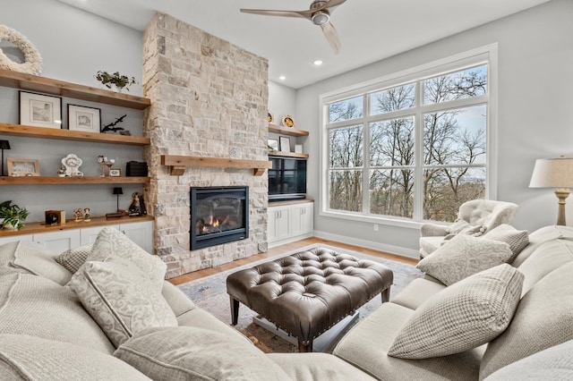 living room with hardwood / wood-style flooring, a stone fireplace, and ceiling fan