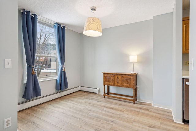 unfurnished room with light wood-type flooring, a textured ceiling, and a baseboard heating unit