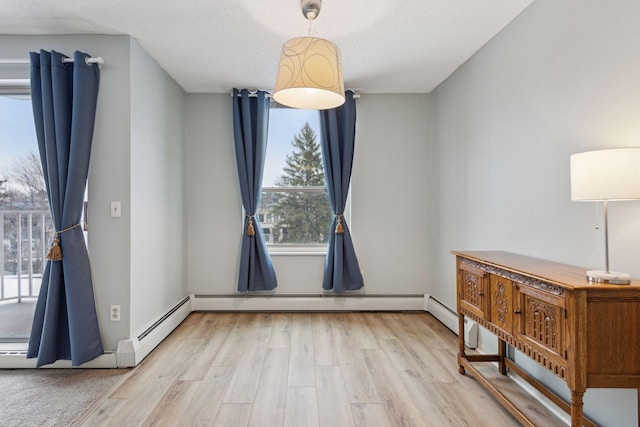 unfurnished dining area featuring a textured ceiling, light hardwood / wood-style floors, and baseboard heating