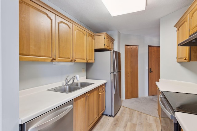 kitchen with sink, light hardwood / wood-style flooring, stainless steel appliances, and a textured ceiling