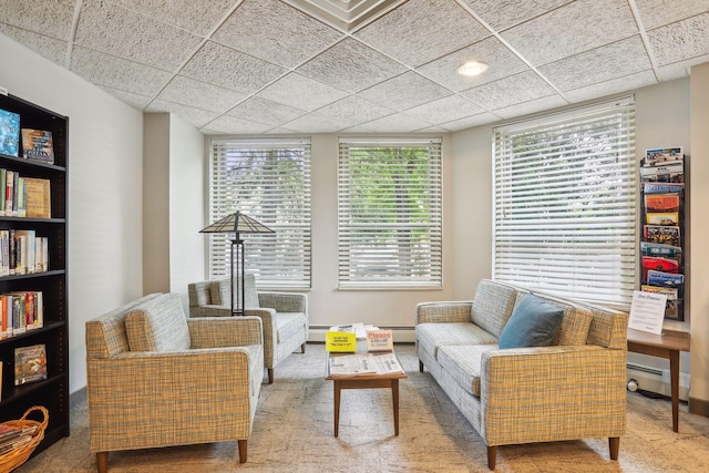 carpeted living room featuring a paneled ceiling and a baseboard heating unit