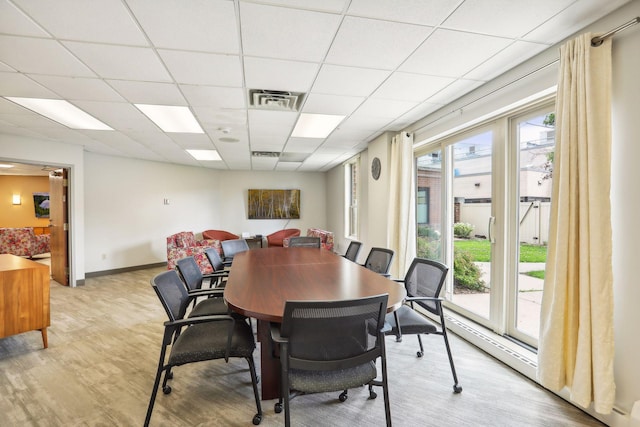 dining space featuring a drop ceiling and light wood-type flooring