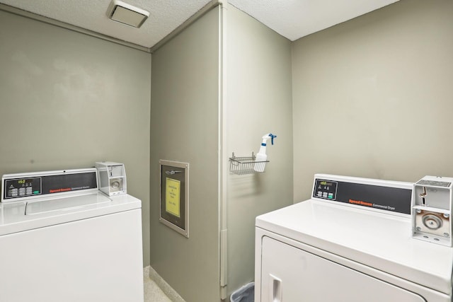 laundry area with a textured ceiling and washing machine and clothes dryer