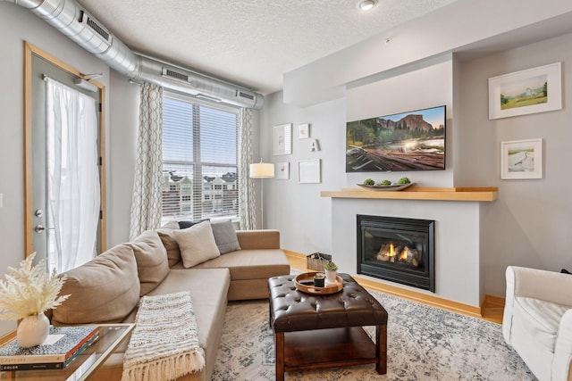 living room with a textured ceiling and a glass covered fireplace