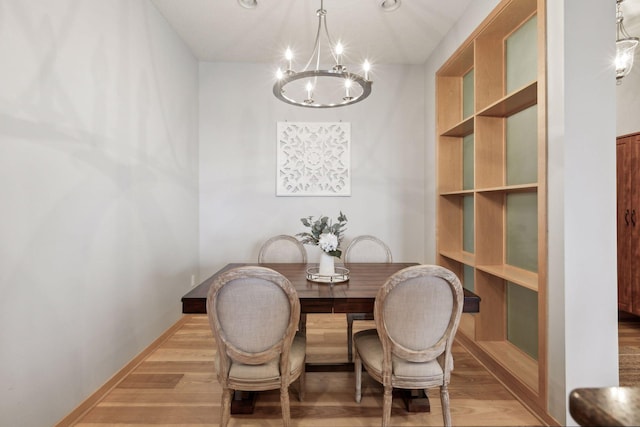 dining space featuring baseboards, an inviting chandelier, and light wood-style floors