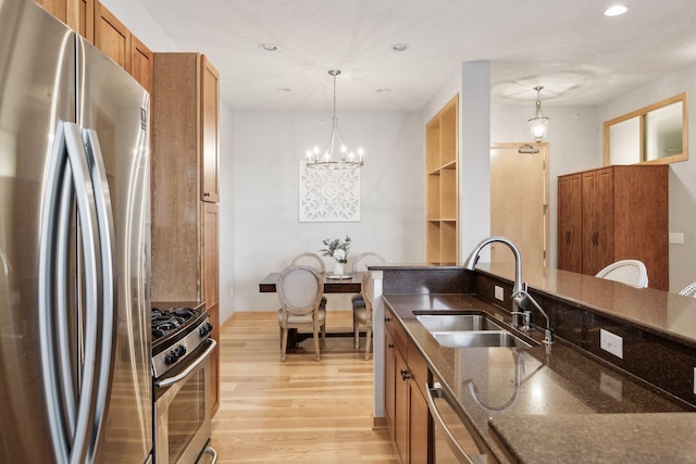 kitchen with a sink, decorative light fixtures, appliances with stainless steel finishes, and dark stone countertops