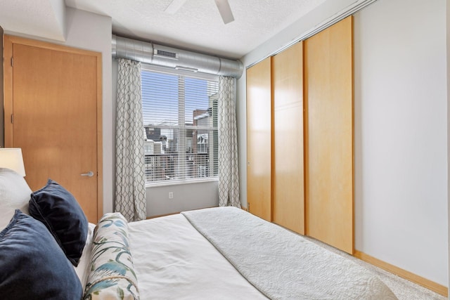 bedroom featuring baseboards, visible vents, a textured ceiling, ceiling fan, and a closet