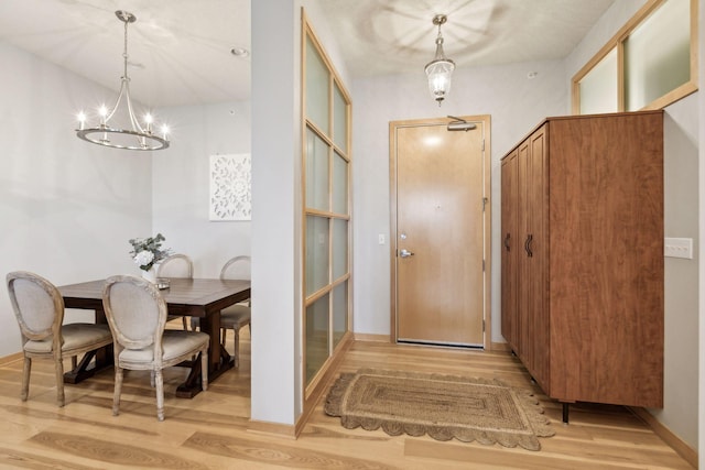 entryway with light wood-type flooring, baseboards, and a chandelier