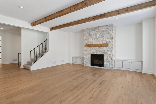 unfurnished living room with light wood-type flooring, stairway, a fireplace, and baseboards