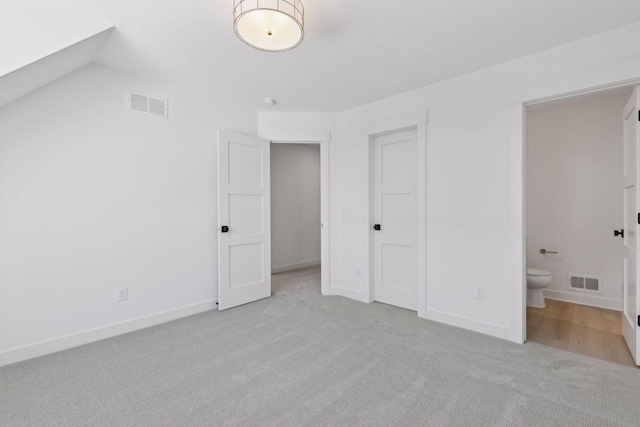 unfurnished bedroom with visible vents, connected bathroom, light carpet, and baseboards