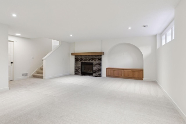 unfurnished living room featuring recessed lighting, light colored carpet, stairway, and baseboards