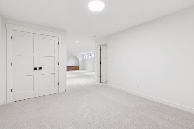 empty room featuring light colored carpet and baseboards