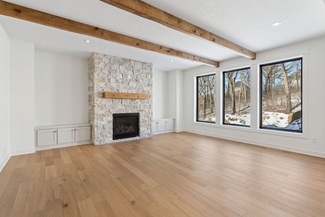 unfurnished living room with light wood-style floors, plenty of natural light, a fireplace, and a textured ceiling