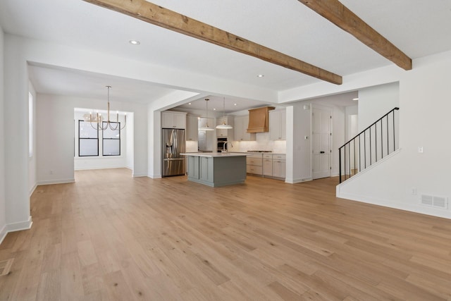 unfurnished living room with light wood finished floors, visible vents, a chandelier, and beam ceiling