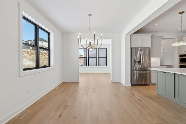 interior space with stainless steel fridge, visible vents, light countertops, and decorative light fixtures